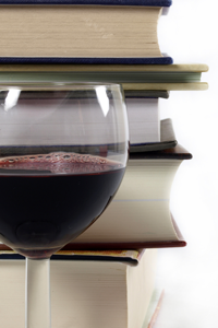 Stack of books behind a wine glass filled with red wine